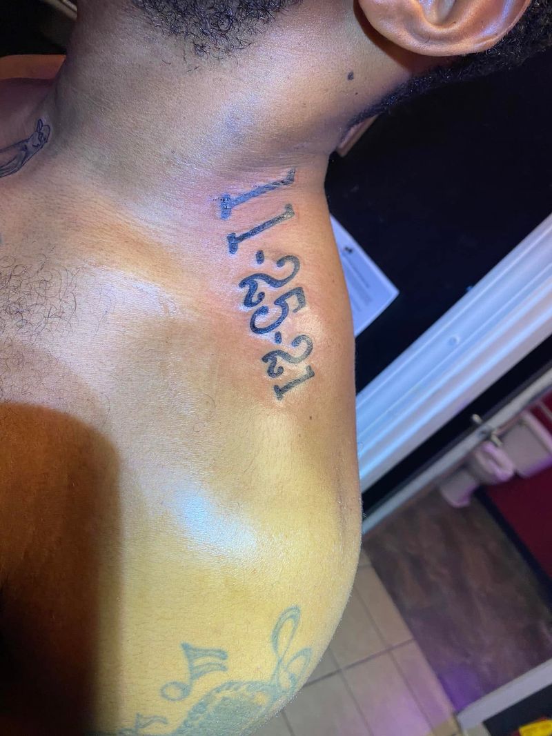 Tattoo of a date in bold numerals on the side of the neck.