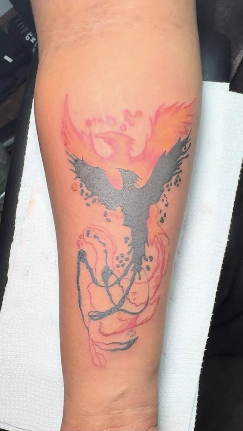 Tattoo of a black phoenix rising from red and orange flames on a forearm.